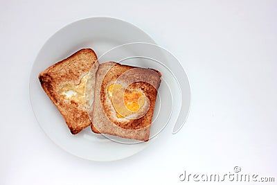 Toast bread with fried egg in a heart shaped hole on plate on white background. Creative Valentine's day Stock Photo