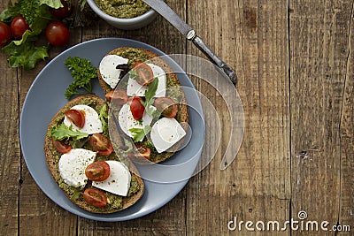 Toast sandwich mozzarella cheese, cherry tomatoes and pesto bruschetta, toast on wooden background. Healthy breakfast, snack. Copy Stock Photo