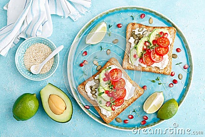 Toasts with feta cheese, tomatoes, avocado, pomegranate, pumpkin seeds and flaxseed sprouts. Diet breakfast. Delicious and healthy Stock Photo