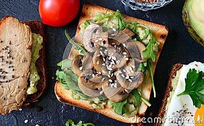 Toasts with mushrooms, arugula, sesame seeds and avocado paste. Useful sandwich. Tasty breakfast. Close-up, top view Stock Photo