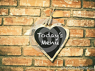 Today`s menu on heart shape chalkboard on concrete wall, restaur Stock Photo