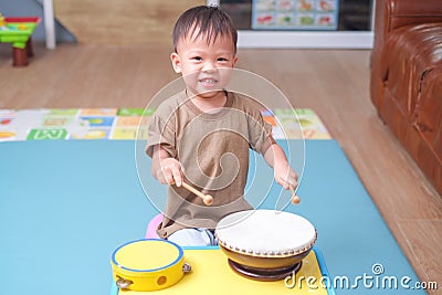 Toddler baby boy child hold sticks & plays a musical instrument drum Stock Photo