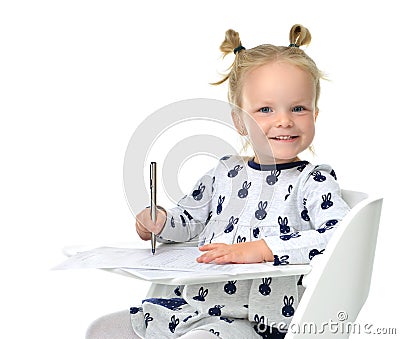 Toddler baby girl learning how to write on a paper book with pen Stock Photo