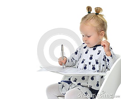 Toddler baby girl learning how to write on a paper book with pen Stock Photo