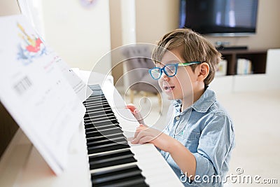 Toddler boy is concentrated on piano and musical notes Stock Photo