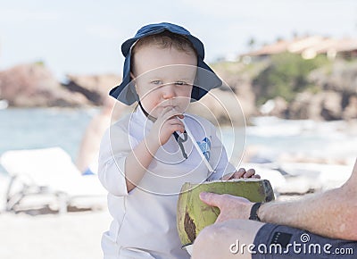 Toddler Boy Drinks from a Coconut on the Beach in Mexico Stock Photo