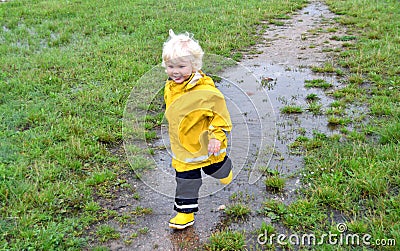 Toddler boy playing in a muddy puddle on a rainy day Stock Photo