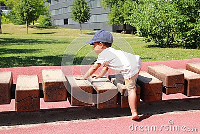 Toddler boy playing on playground - unstable wooden bridge Stock Photo