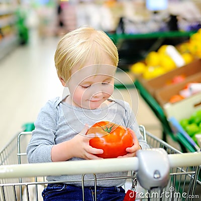 Toddler boy sitting in the shopping cart in a food store Stock Photo