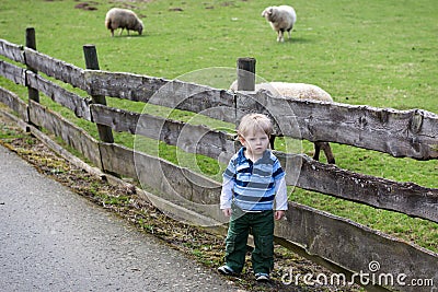 Toddler child standing in front of a wooden fence Stock Photo