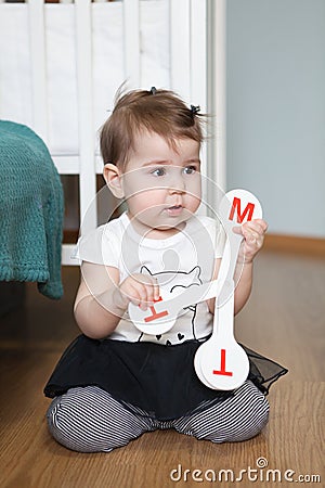 Toddler child with toy with letters, alphabet characters. Little girl sitting on floor of domestic room Stock Photo