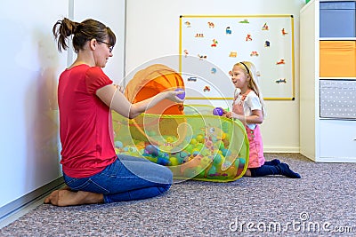 Toddler girl in child occupational therapy session doing playful exercises with her therapist. Stock Photo