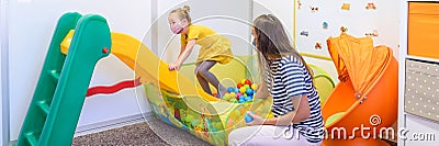 Toddler girl in child occupational therapy session doing playful exercises with her therapist during Covid-19 pandemic. Stock Photo