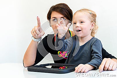 Toddler girl in child occupational therapy session doing sensory playful exercises with her therapist. Stock Photo