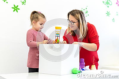 Toddler girl in child occupational therapy session doing sensory playful exercises with her therapist. Stock Photo