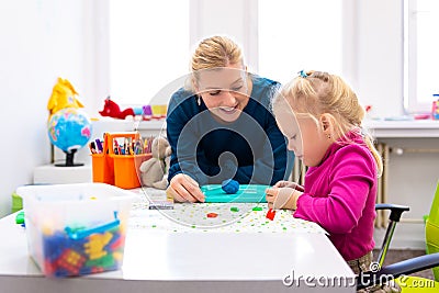 Toddler girl in child occupational therapy session doing sensory playful exercises with her therapist. Stock Photo