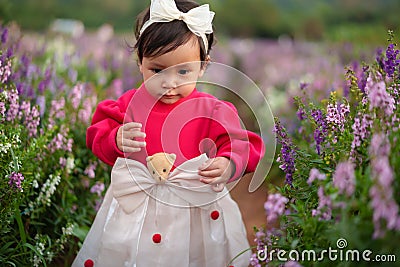 toddler girl enjoying Angelonia flower blooming Stock Photo