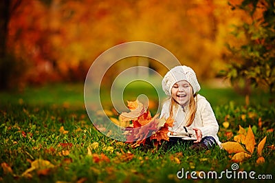 Toddler girl have fun with fallen golden leaves Stock Photo