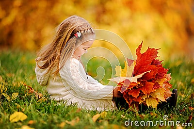 Toddler girl have fun with fallen golden leaves Stock Photo