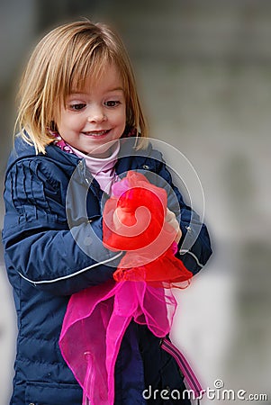 Toddler girl plays with silk scarfs Stock Photo