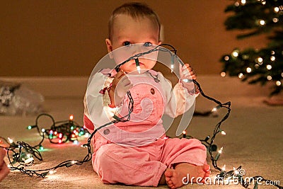 Toddler girl with string of Christmas lights Stock Photo