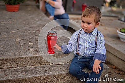 Toddler holding a candle on the grave Stock Photo