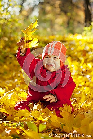 Toddler with maple leaves in autumn Stock Photo