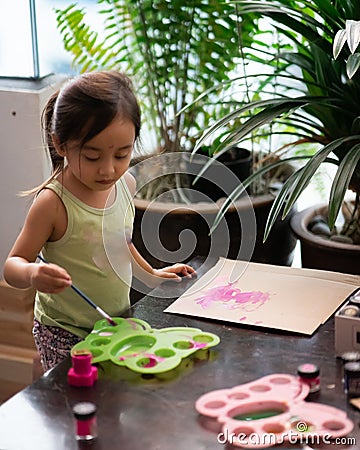 Toddler painting on the recycled cardboard at home Stock Photo