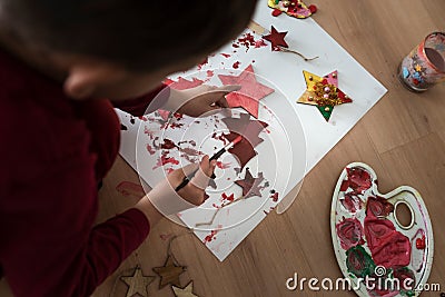 Toddler painting wooden decorations red Stock Photo