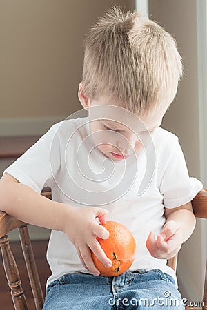 Toddler peeling orange Stock Photo