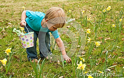 Toddler picking up Easter egg Stock Photo