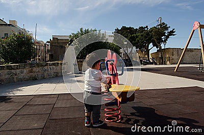 Toddler playing alone in the park - lonely child Stock Photo