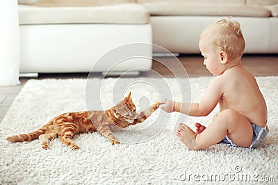 Toddler playing with cat Stock Photo