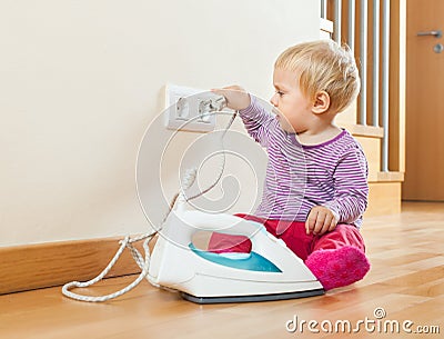 Toddler playing with electric iron Stock Photo