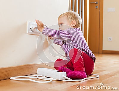 Toddler playing with electrical extension Stock Photo