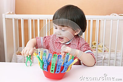 Toddler plays with clothes pins Stock Photo