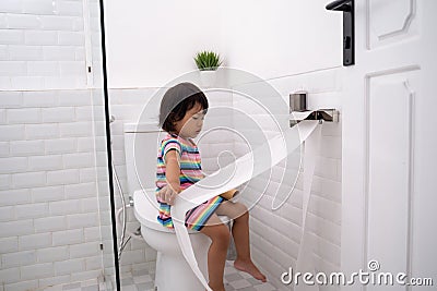 Toddler pulling out toilet paper Stock Photo