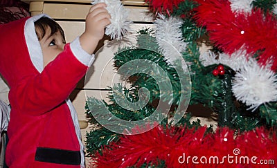 Toddler putting christmas decoration on christmas tree Stock Photo