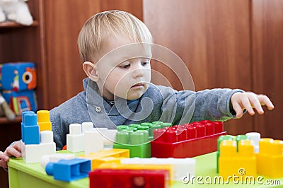 Toddler reaching for a toy constuctor indoor Stock Photo