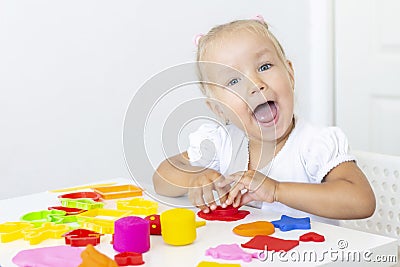 Toddler sculpts from colored plasticine on a white table. Stock Photo