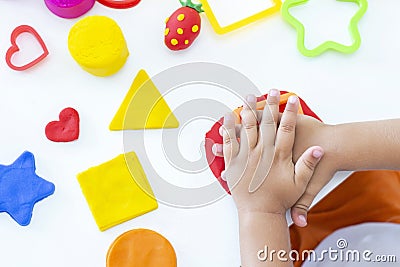 Toddler sculpts from colored plasticine on a white table. Stock Photo