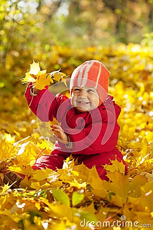 Toddler sitting on maple leaves Stock Photo