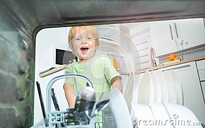 Toddler take dishes from the dishwasher at kitchen Stock Photo