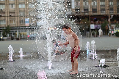 Toddler walking in a splashing water fountain Stock Photo