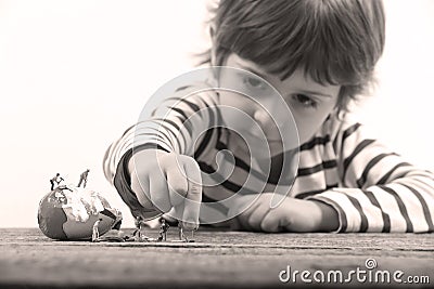 Toddler watching miniature people cracking an egg Stock Photo