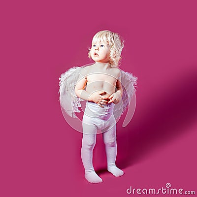 Toddler wearing angel feather wings and stand on the pink Stock Photo