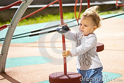 Toddler 1 year girl boy Caucasian, child play on the playground, baby with wavy hair in the wind, horizontal summer Stock Photo