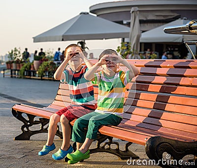 Toddlers boy and his sibling brother sitting on a bench by the c Stock Photo