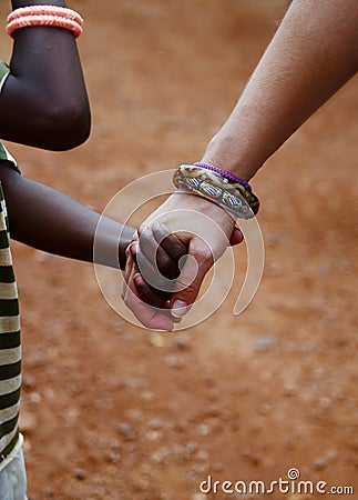 Together for Africa: Holding Hands between poor African child and white caucasian Woman Stock Photo