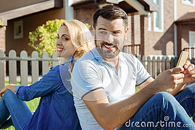 Happy couple sitting back to back in backyard Stock Photo